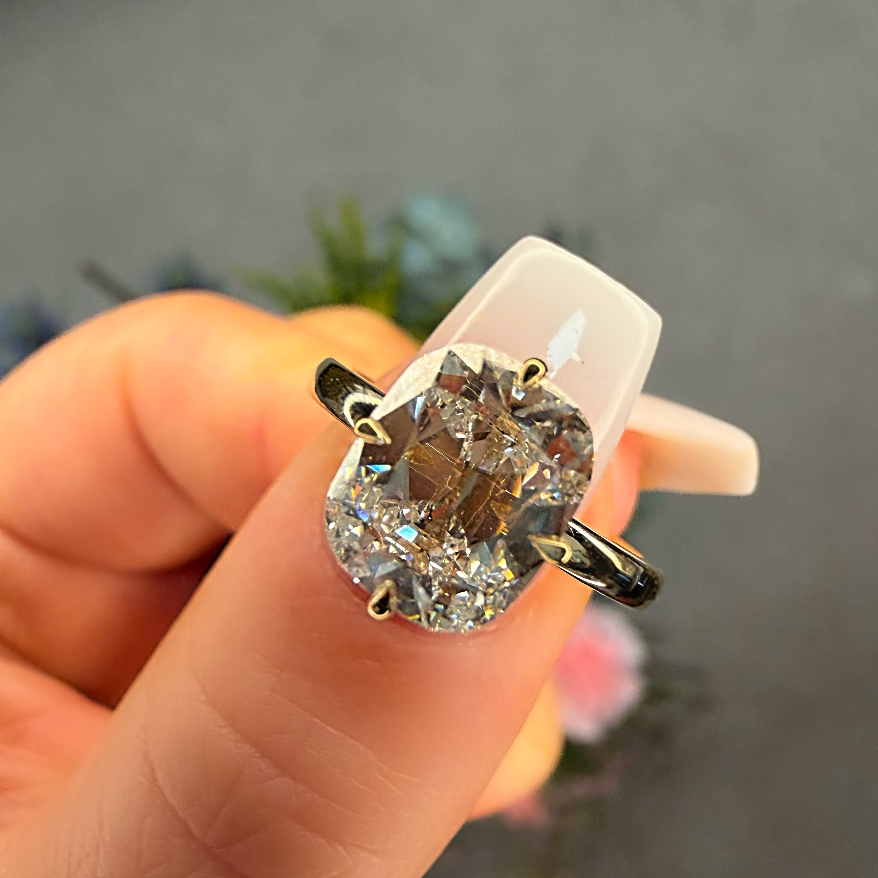 Diamond ring held in a hand with a blurred background