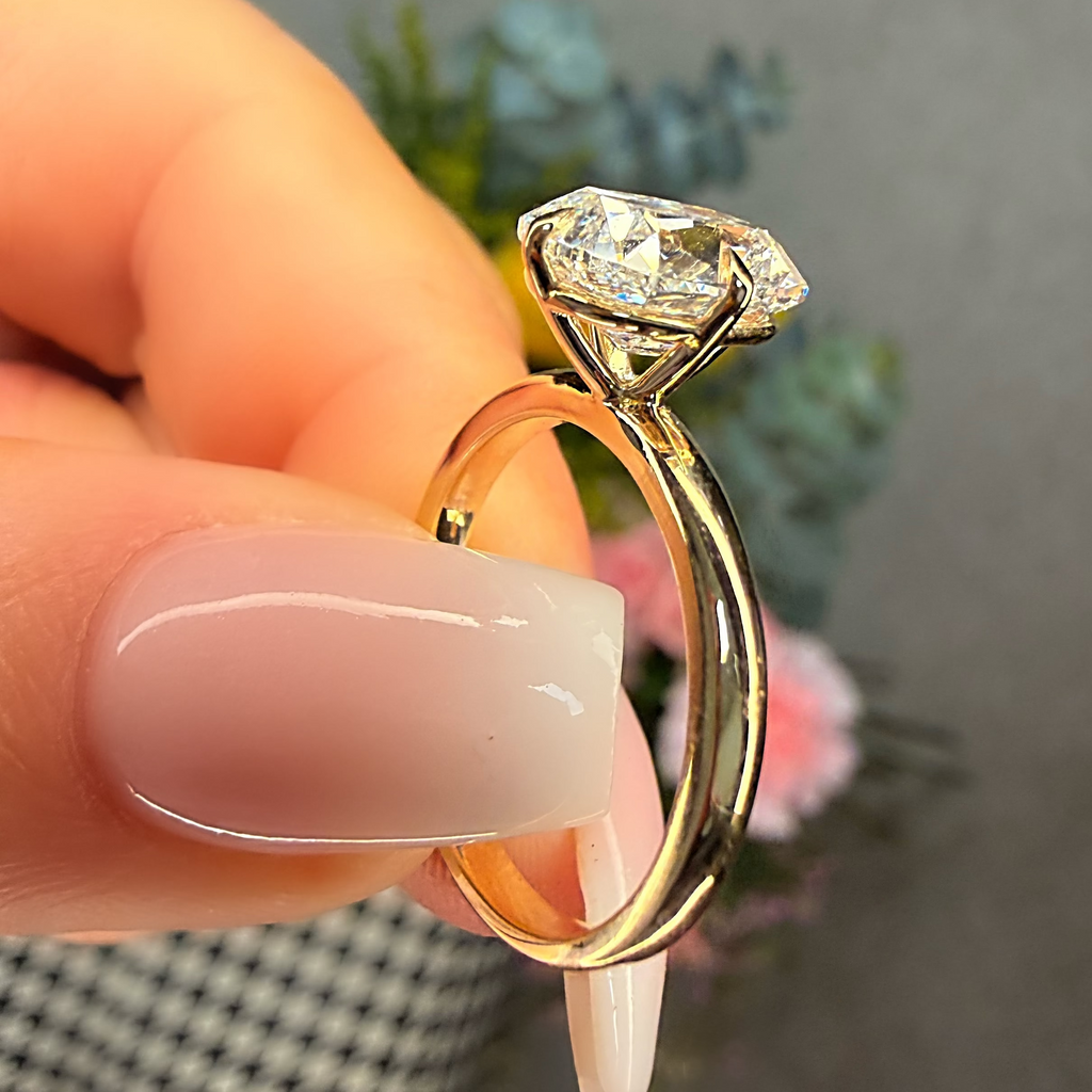 Gold ring with a diamond held by a hand against a blurred background