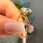 Gold ring with a diamond held by a hand against a blurred background