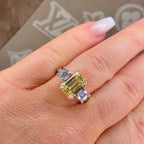 Ring with a yellow gemstone and smaller diamonds on a hand, with a patterned background.