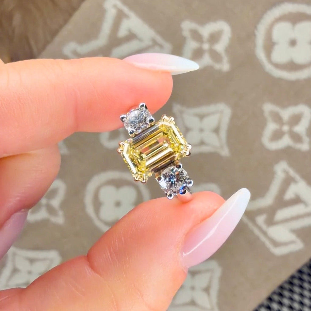 Gold ring with a yellow gemstone held between fingers on a patterned surface