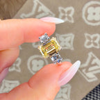 Gold ring with a yellow gemstone held between fingers on a patterned surface