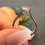 Silver ring with a heart-shaped diamond held by a hand against a blurred background