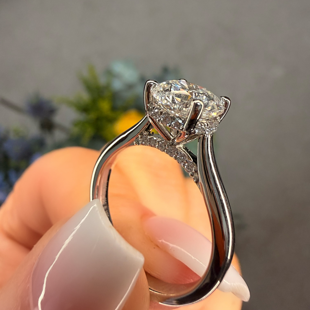 Silver ring with a large diamond held in a hand against a blurred background