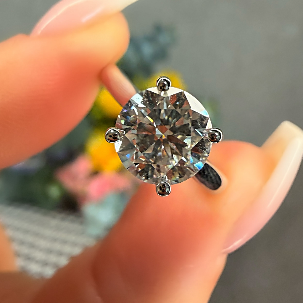 Diamond ring held between fingers against a blurred background