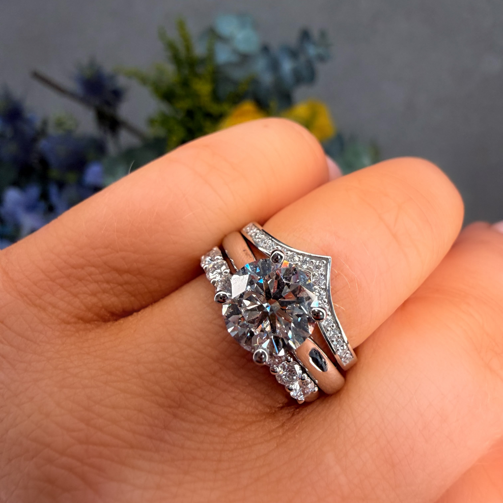Silver ring with gemstones on a hand against a blurred floral background