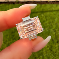 Diamond ring held by a hand with a blurred green background