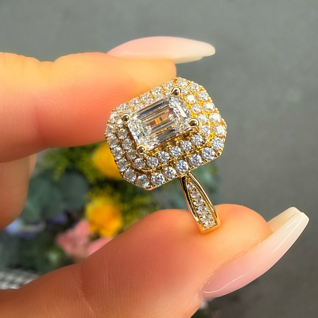 Gold ring with diamond accents held by a hand against a blurred background
