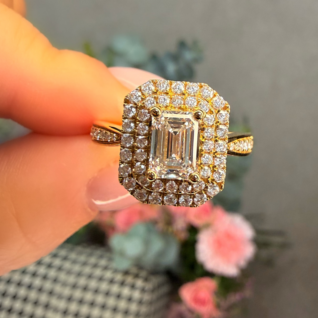 Gold ring with a large diamond held by a hand against a blurred background