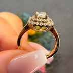 Gold ring with diamonds held by a hand against a blurred background