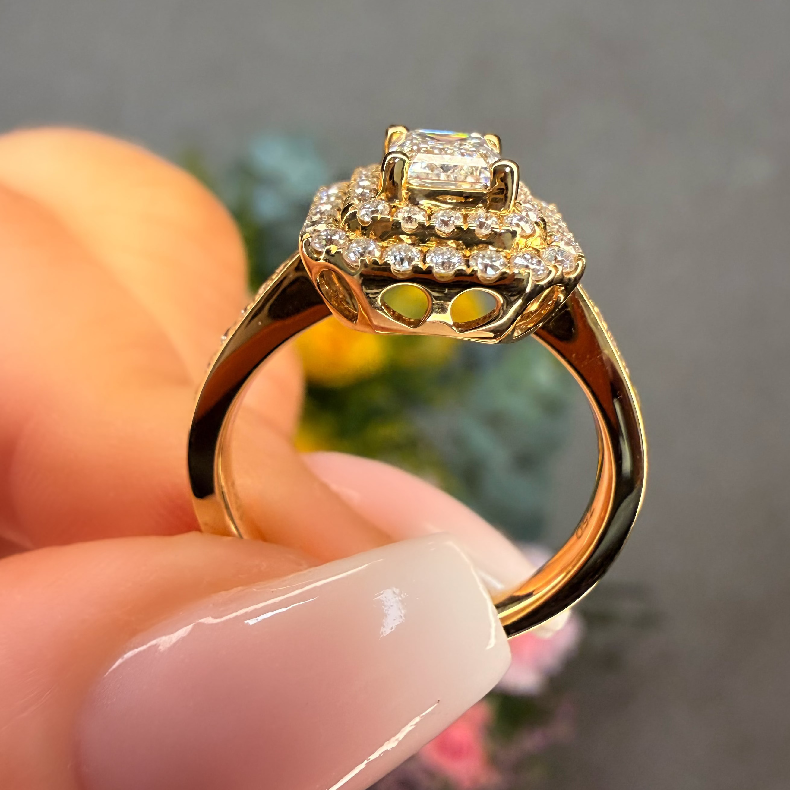 Gold ring with diamonds held by a hand against a blurred background