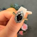 Ring with a black gemstone held in a hand against a blurred background