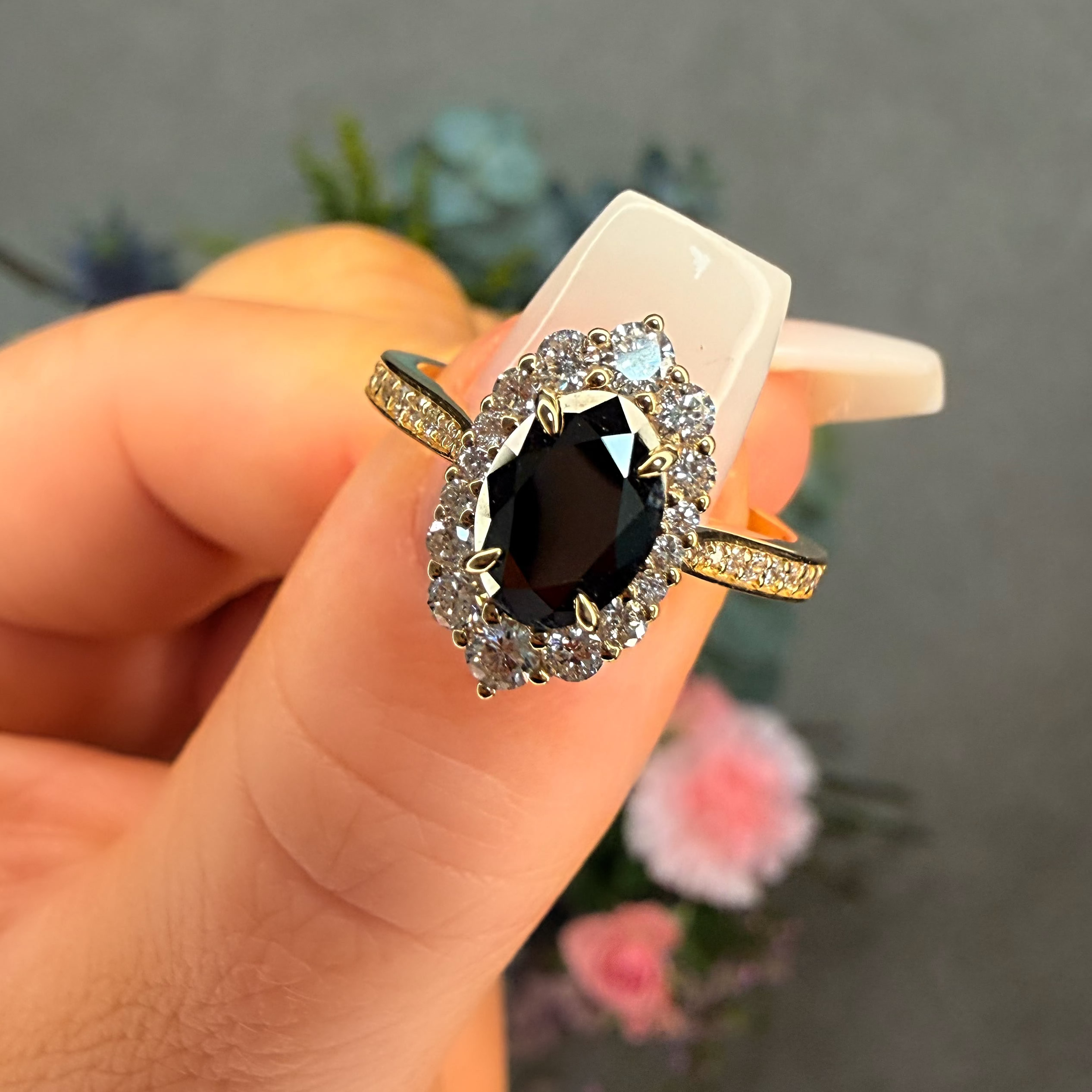 Ring with a black gemstone held in a hand against a blurred background
