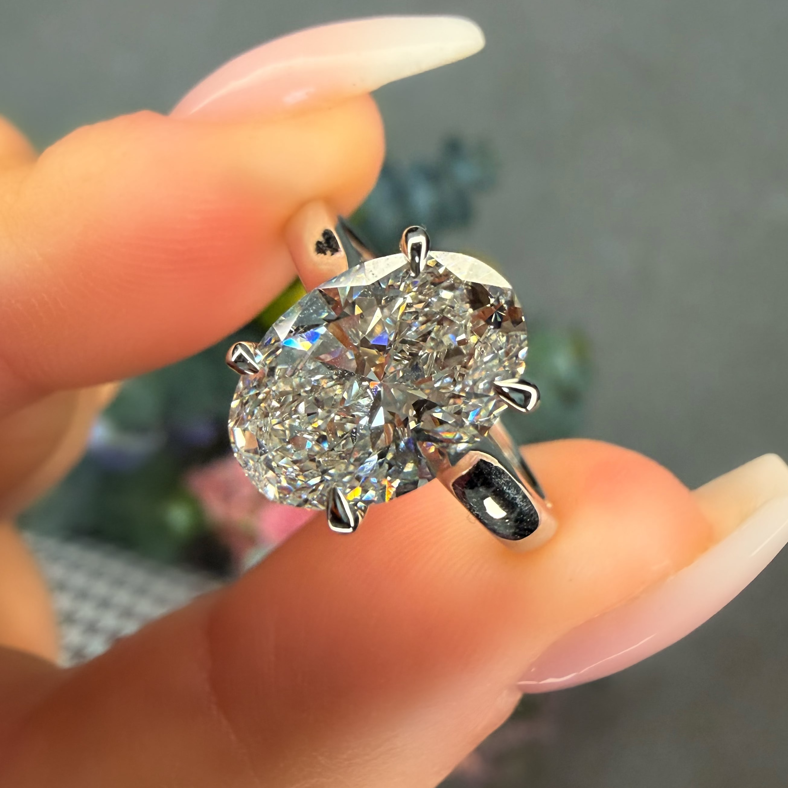 Diamond ring held between fingers with a blurred background