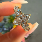 Gold earrings with clear gemstones held between fingers against a blurred background