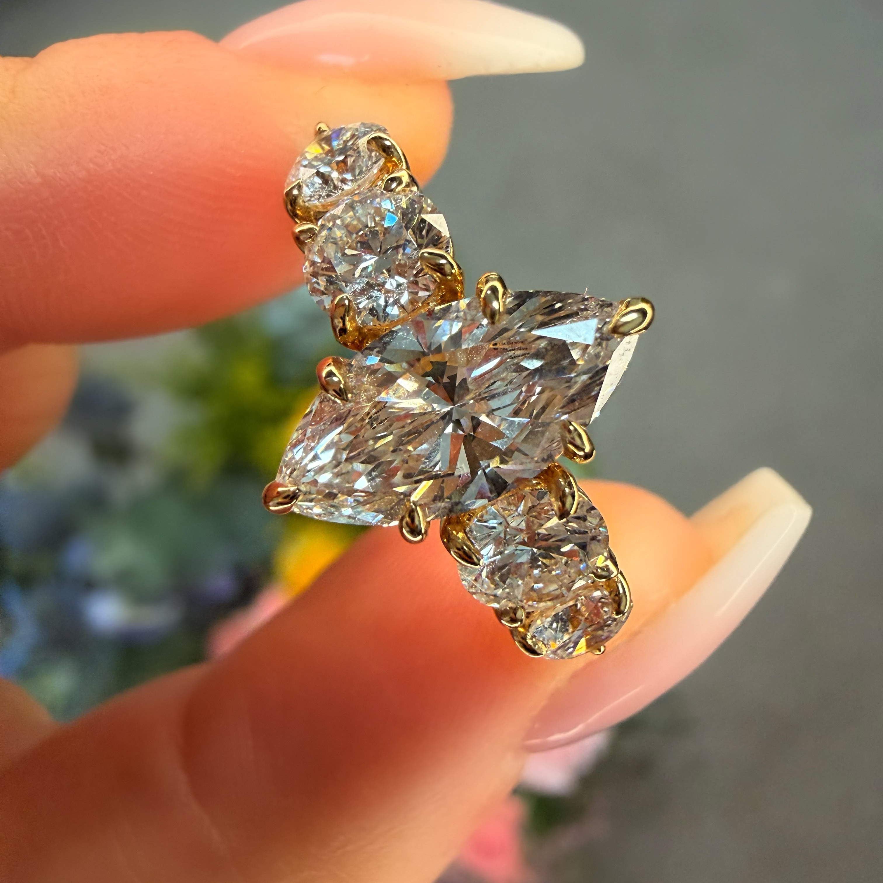 Gold earrings with clear gemstones held between fingers against a blurred background