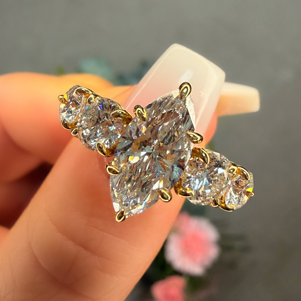 Gold and diamond earring held by a hand with a blurred background