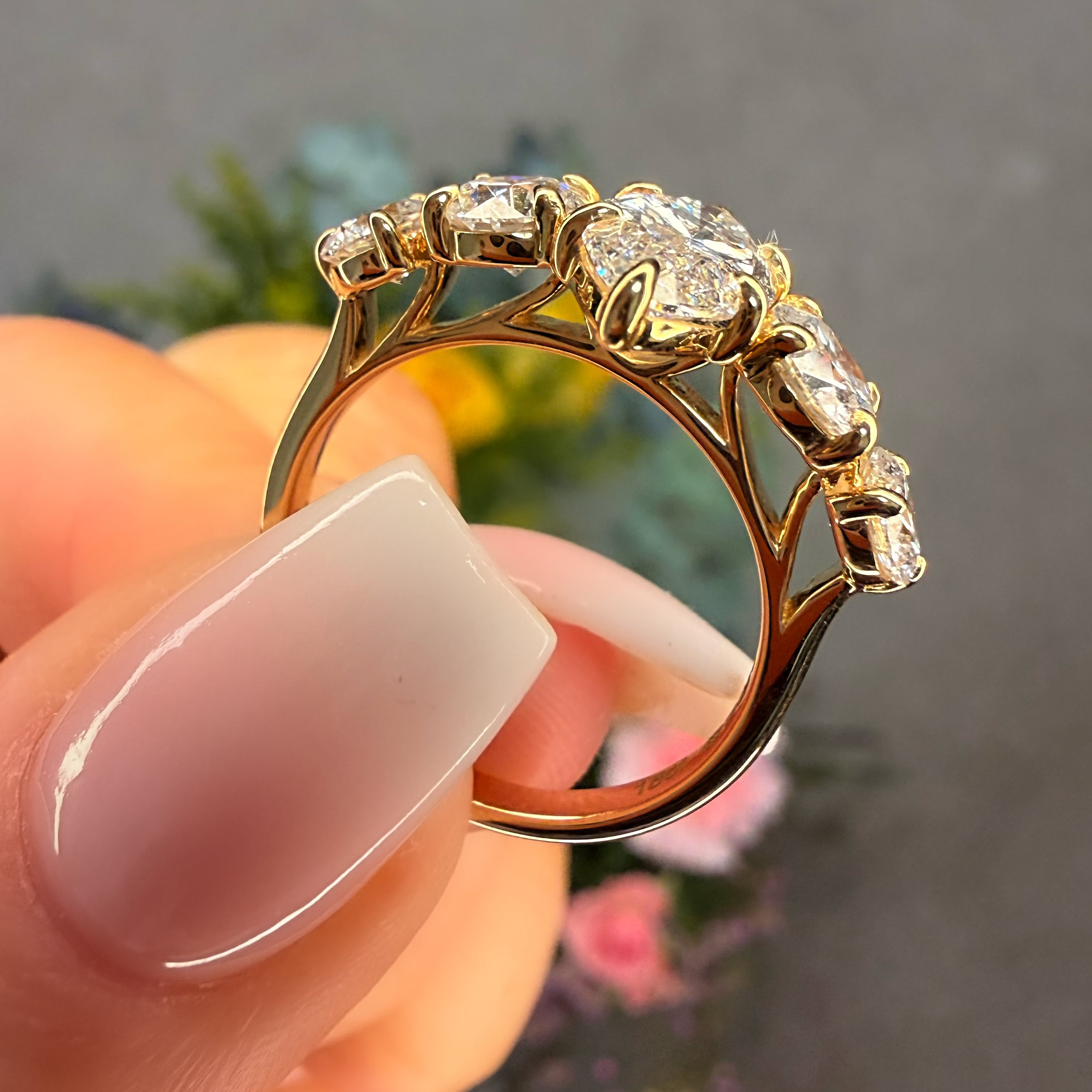 Gold ring with diamonds held by a hand against a blurred background