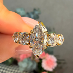Gold ring with a large diamond held by a hand against a blurred background