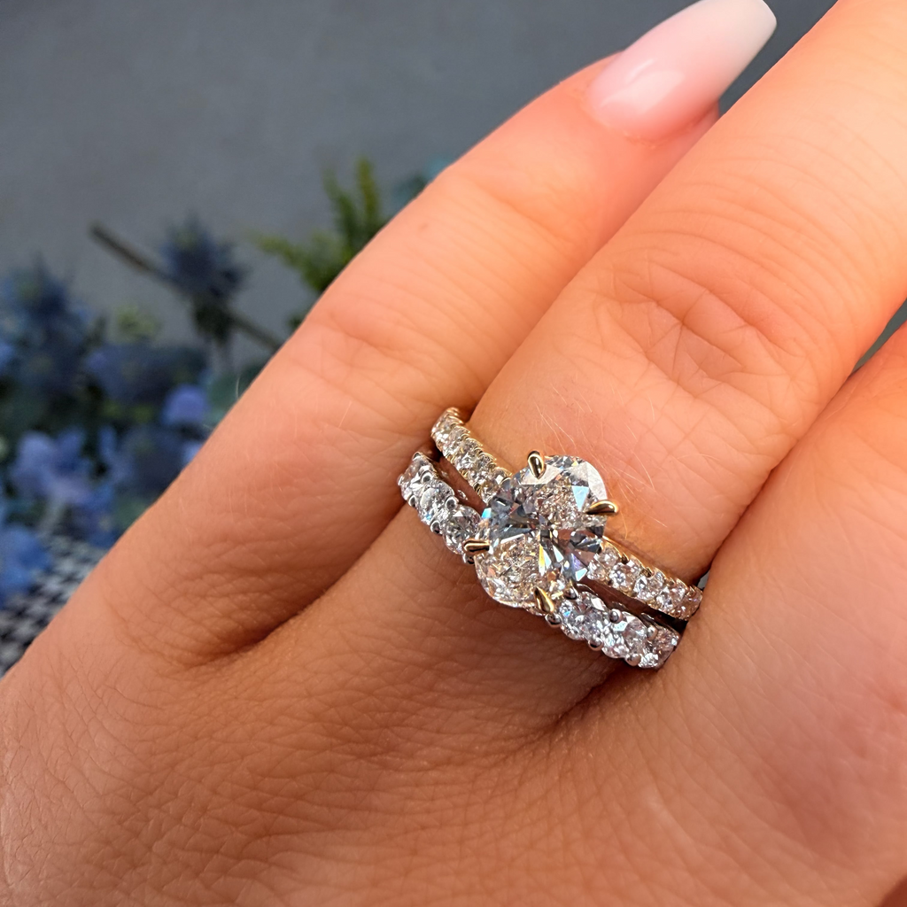 Close-up of a hand wearing a diamond ring with a blurred natural background
