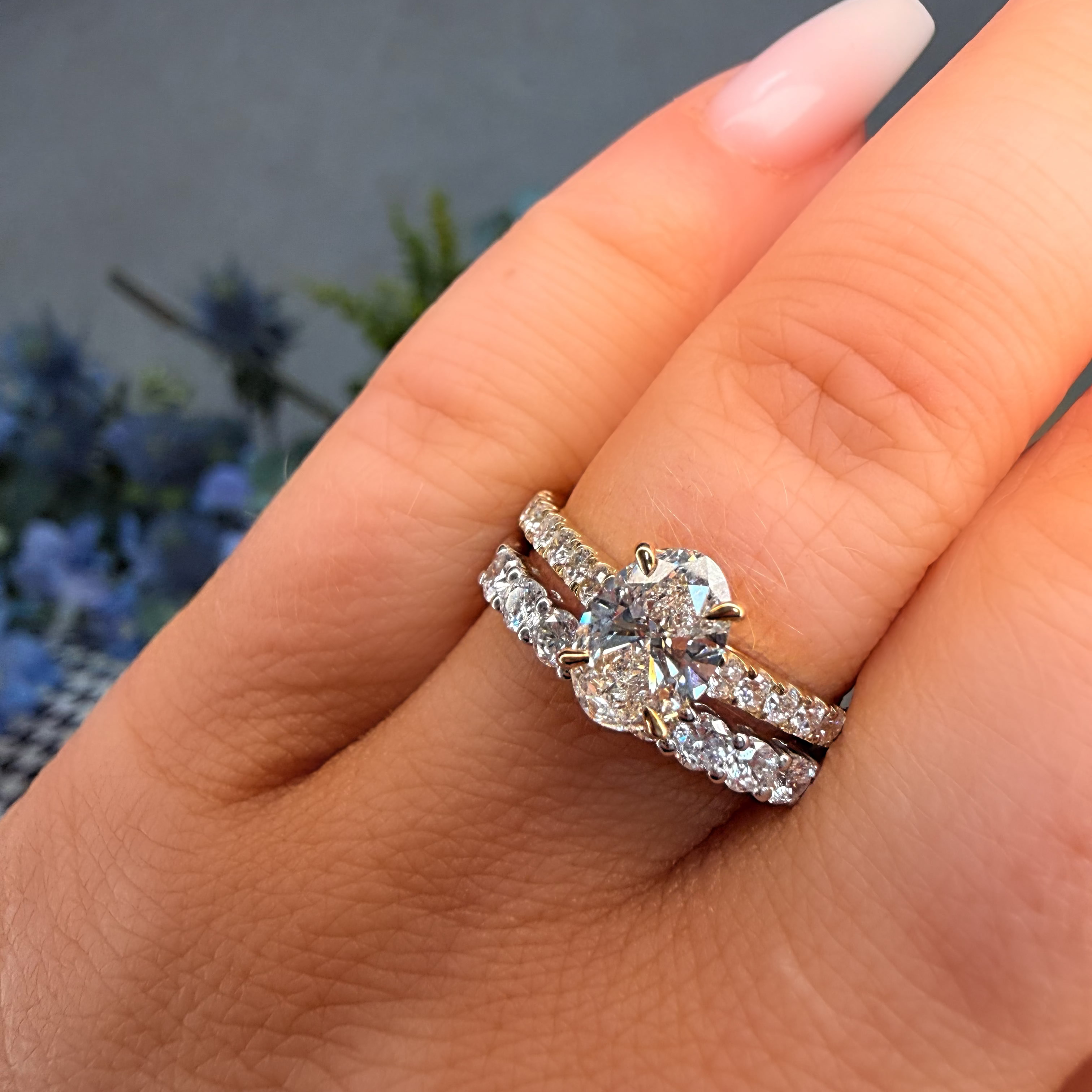 Close-up of a hand wearing a diamond ring with a blurred natural background