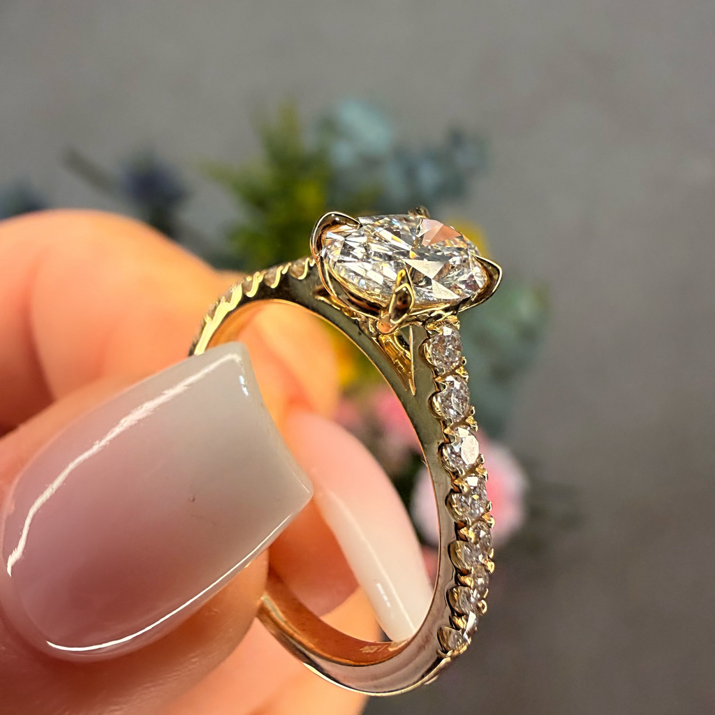 Gold ring with a diamond held by a hand against a blurred background