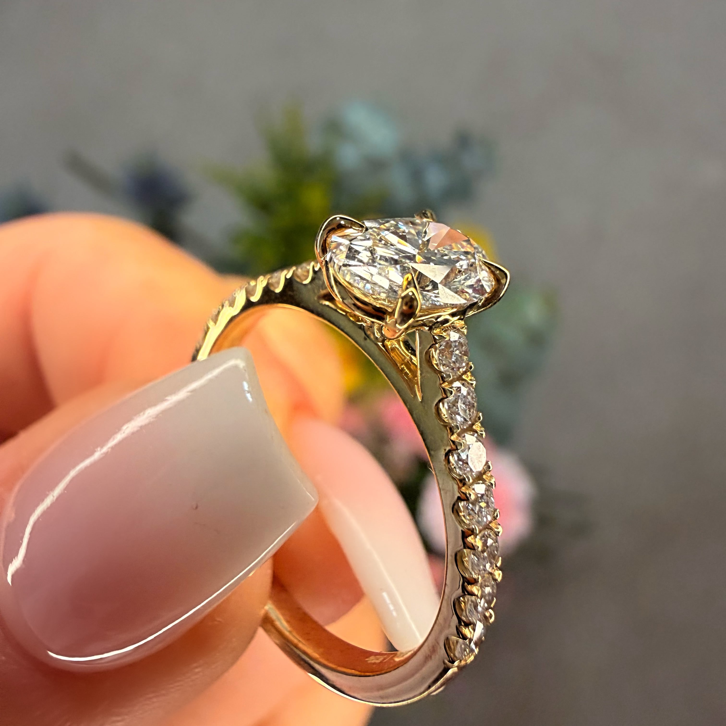 Gold ring with a diamond held by a hand against a blurred background