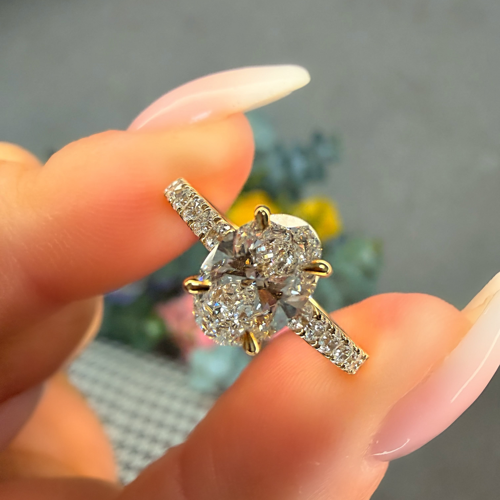 Gold and diamond ring held between fingers with a blurred background