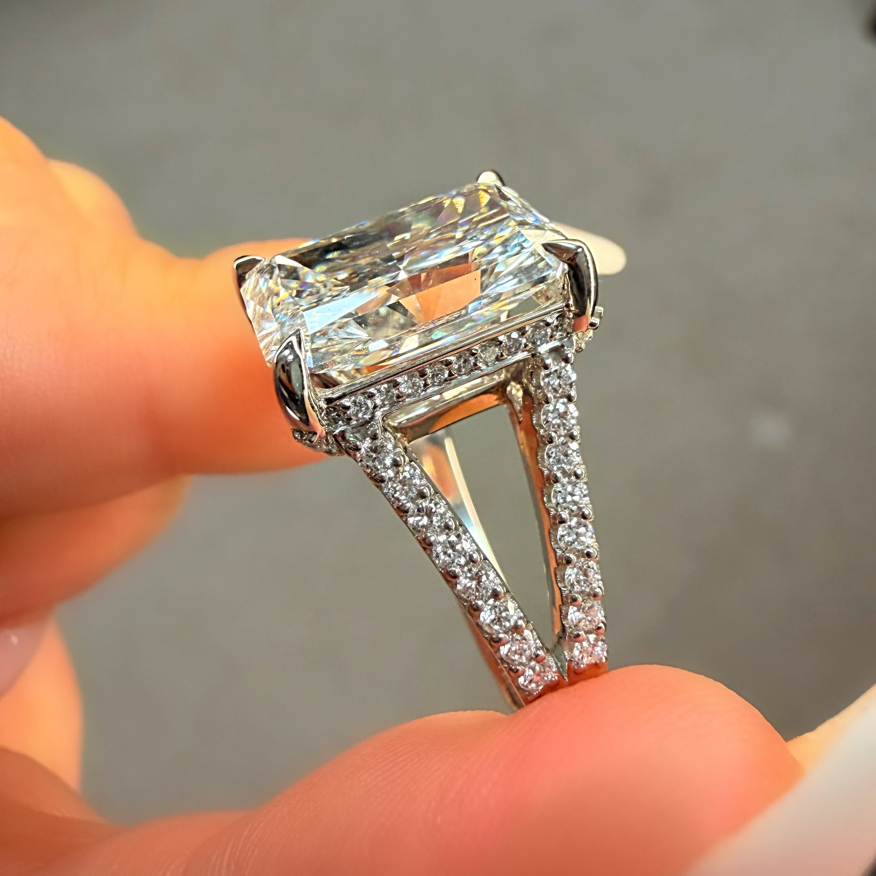 Diamond ring held in a hand with a neutral background