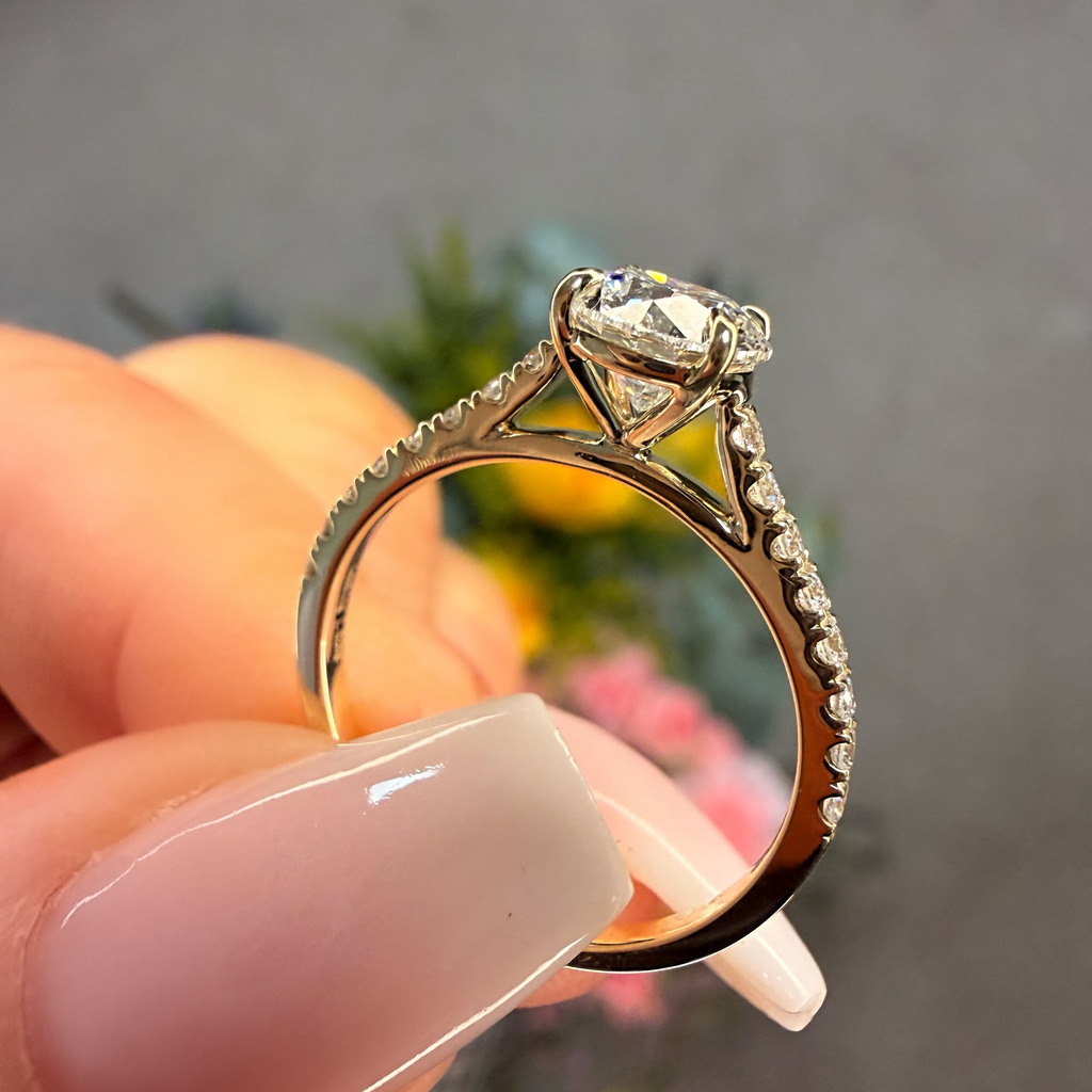 Gold ring with a diamond held between fingers against a blurred background