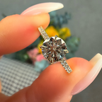 Diamond ring held between fingers with a blurred background