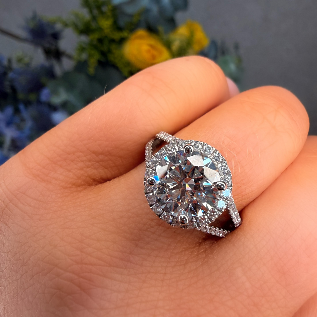 Silver ring with a large diamond on a hand, with a blurred floral background