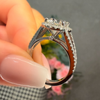 Silver ring with a large diamond held by a hand against a blurred background