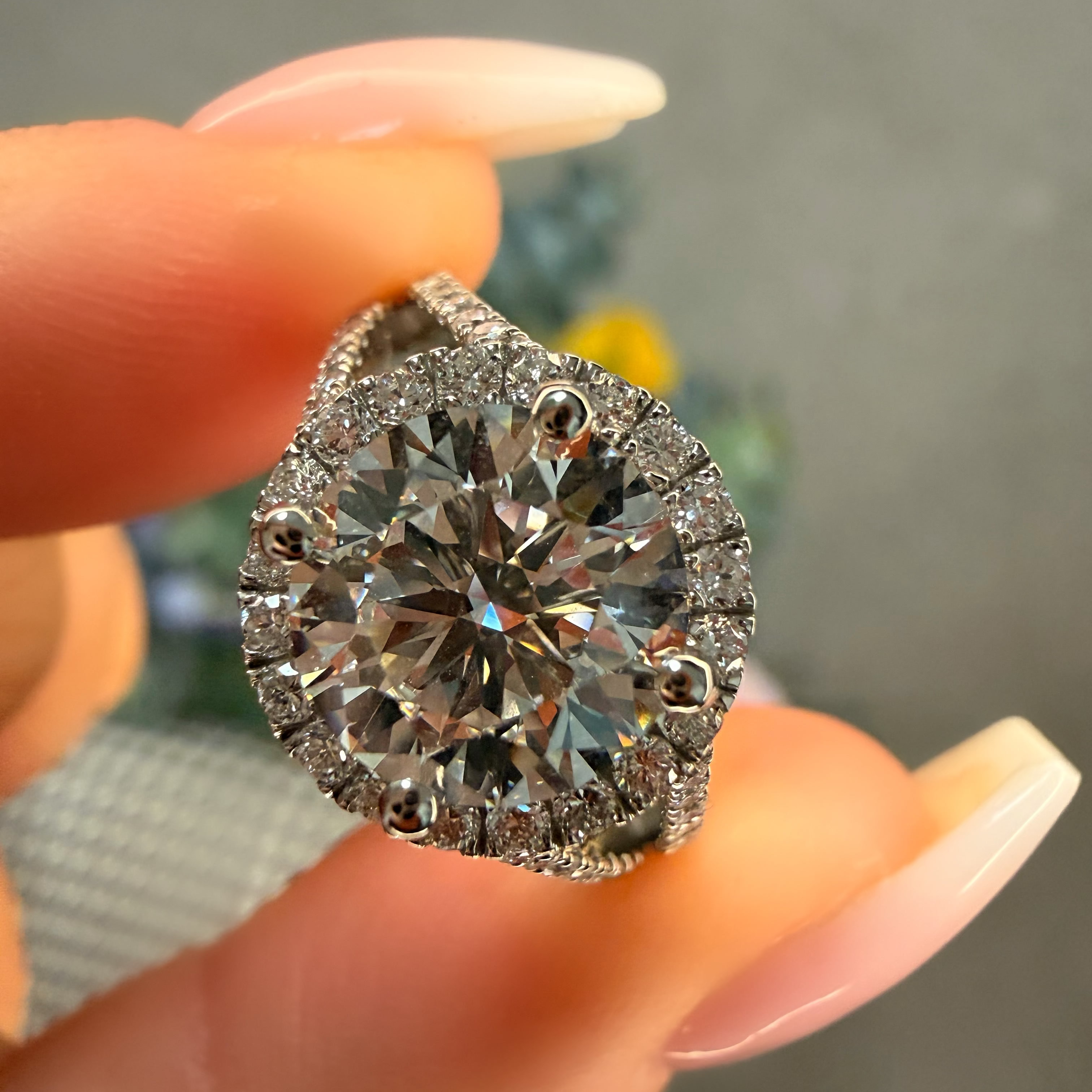 Diamond ring held between fingers with a blurred background