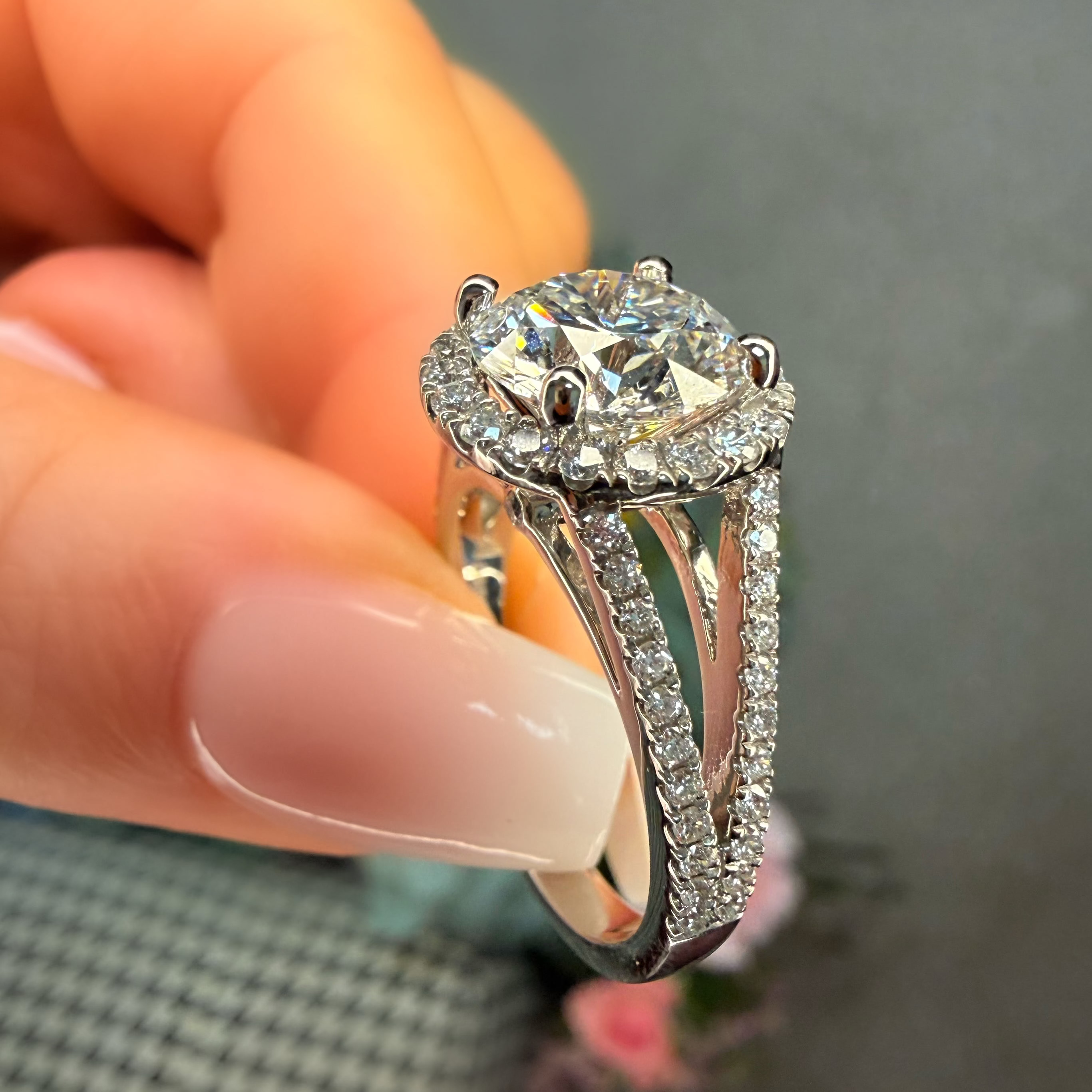 Silver ring with a diamond held between fingers against a neutral background