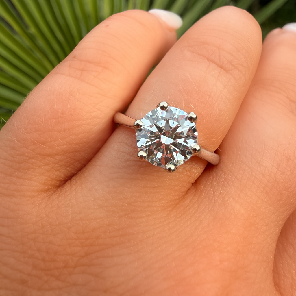 Diamond ring on a finger with a blurred green leaf background