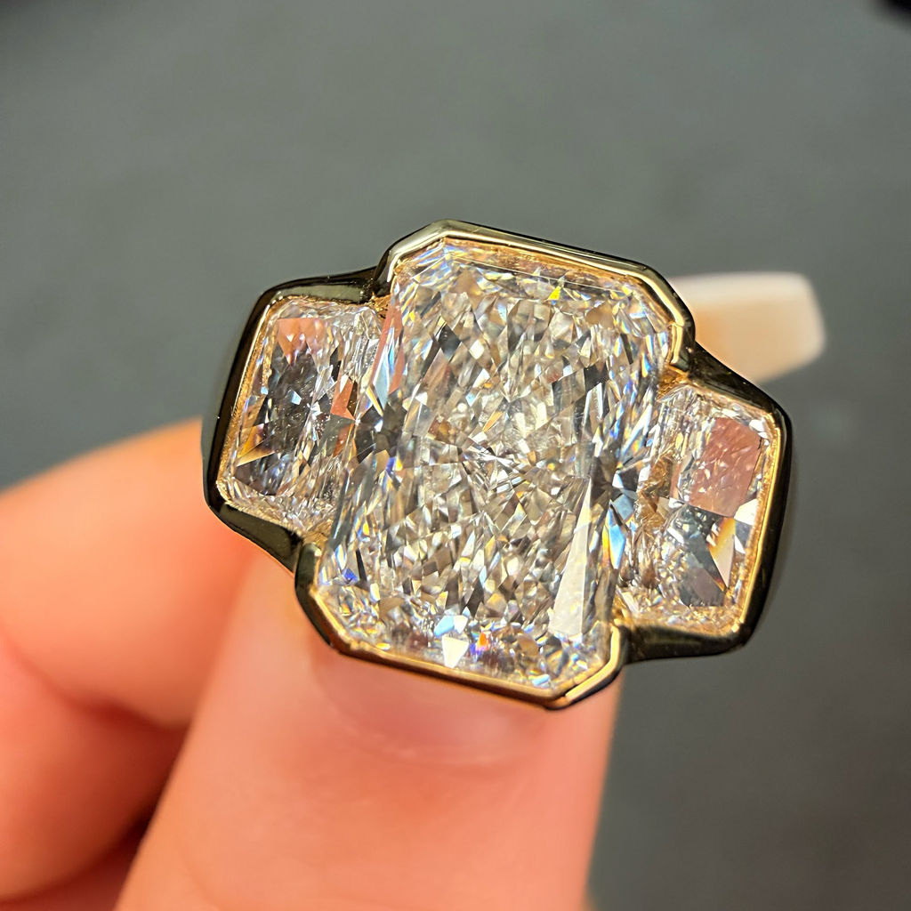 Gold ring with a large diamond held in a hand against a neutral background