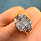 Gold ring with a large diamond held between fingers against a neutral background