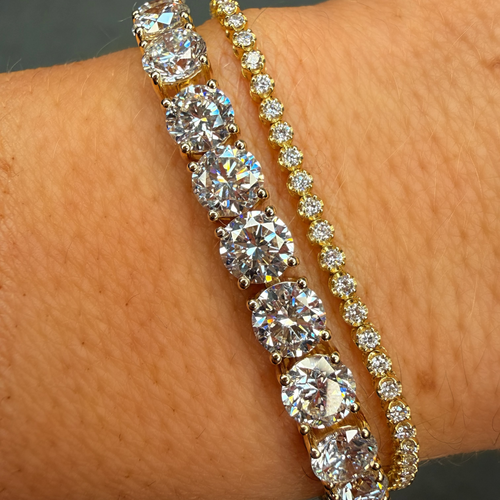 Two diamond bracelets on a wrist against a neutral background