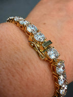 Gold bracelet with clear gemstones on a wrist against a neutral background