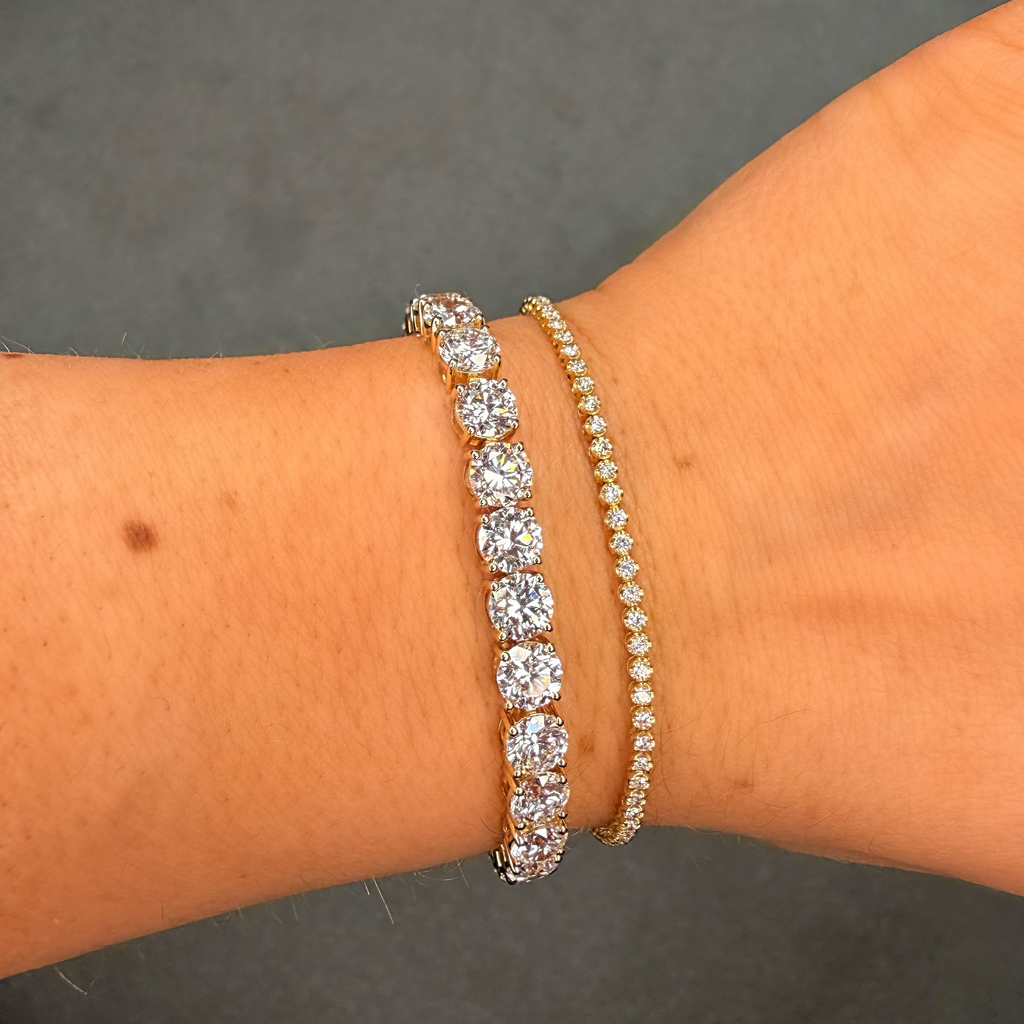 Two diamond bracelets on a person's wrist against a dark background