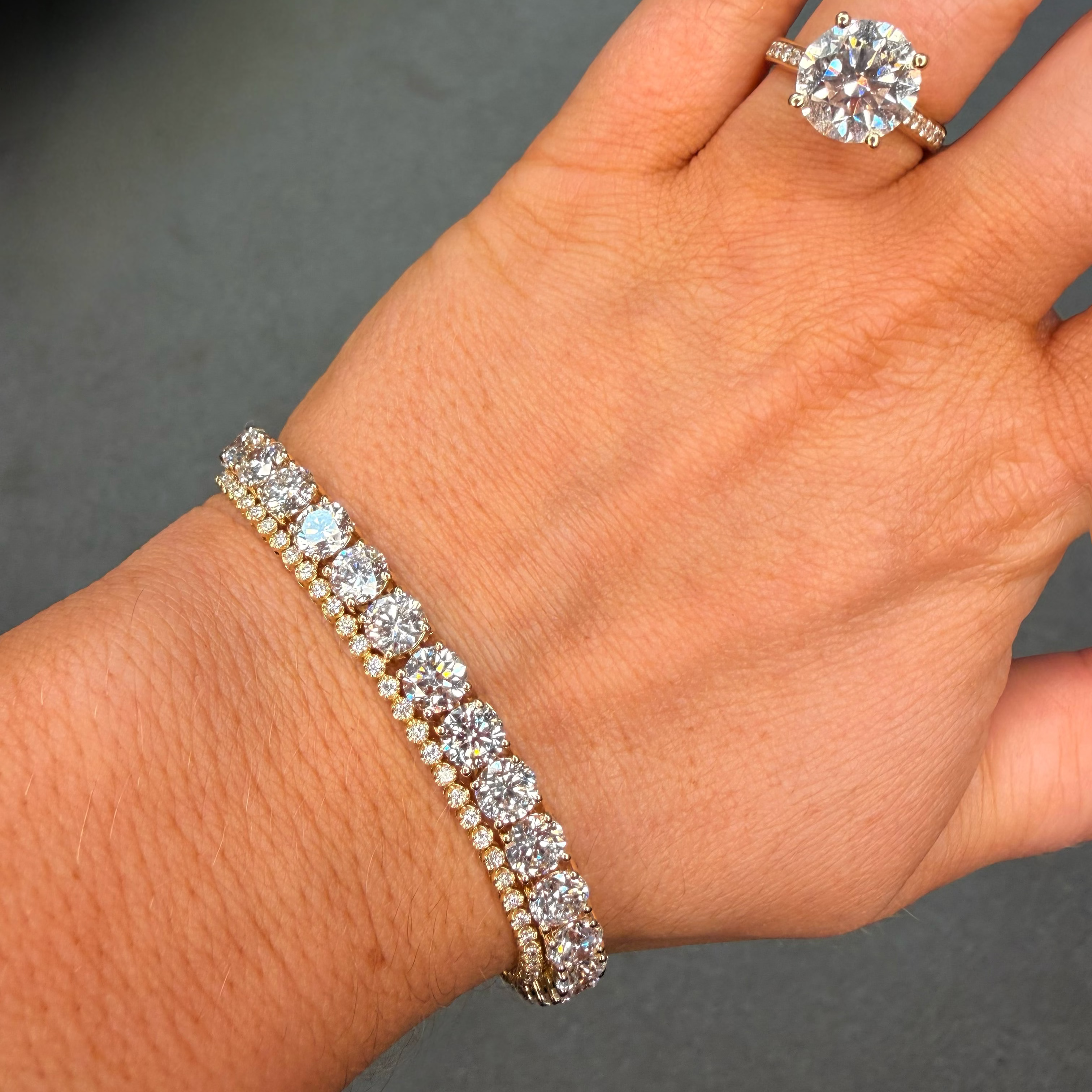 Hand wearing a diamond bracelet and ring on a dark background