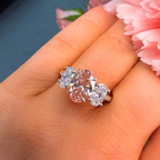 Ring with three diamonds on a hand with pink flowers in the background