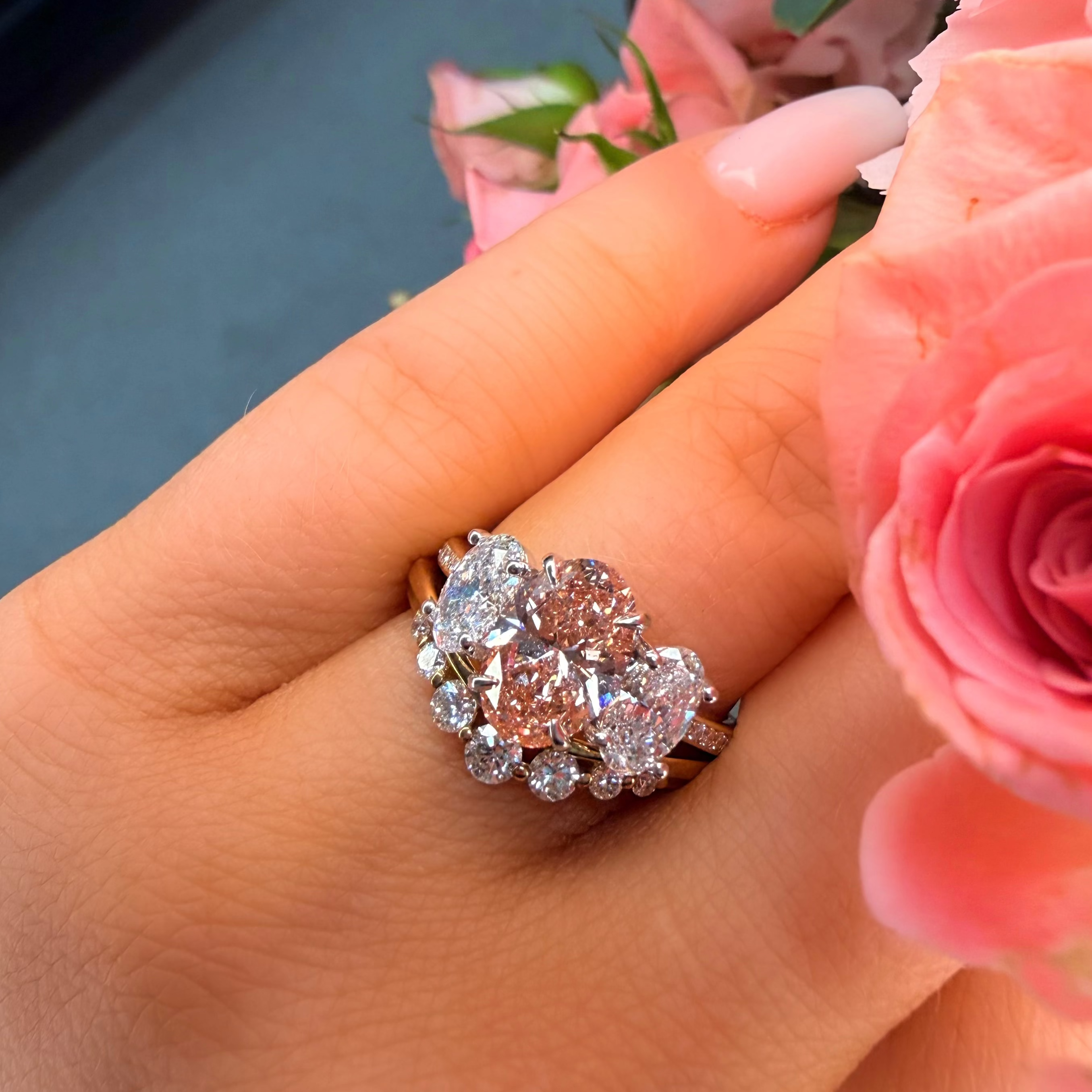 Elegant diamond ring on a hand with pink flowers in the background
