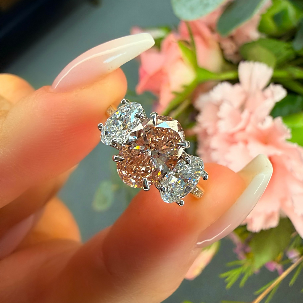 Diamond earrings held by a hand with a floral background