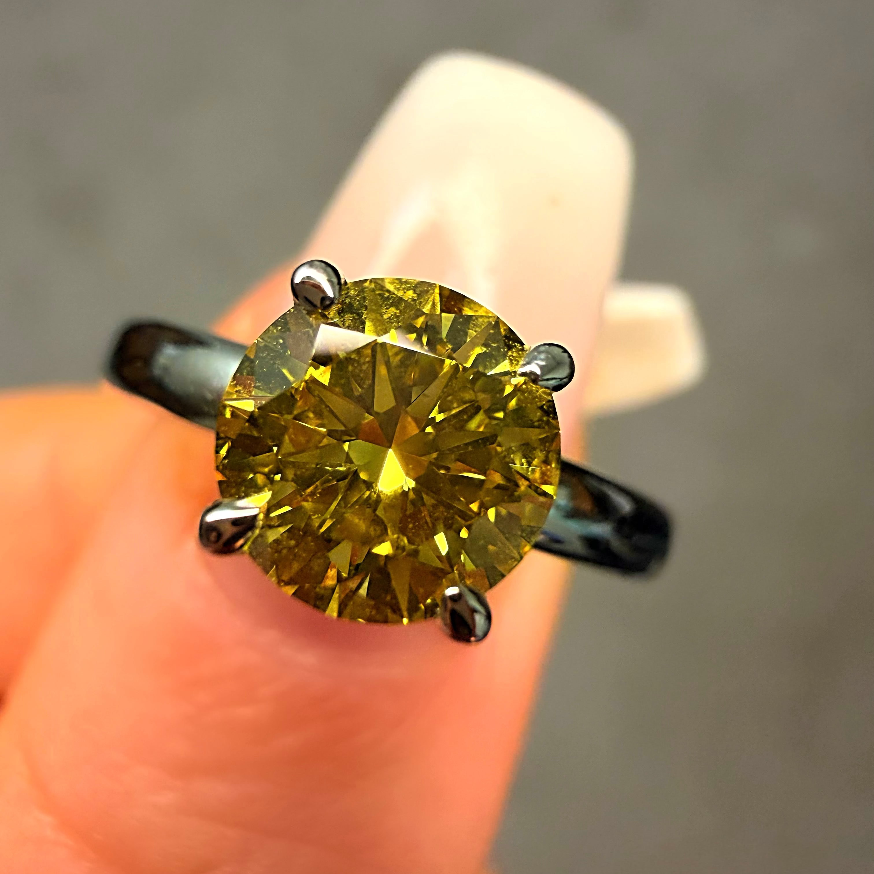 Yellow diamond ring held on a finger against a neutral background