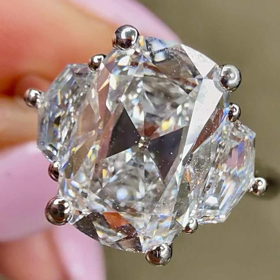 Close-up of a diamond ring held by a hand with a blurred background