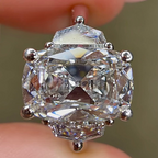 Close-up of a diamond earring held between fingers with a blurred background