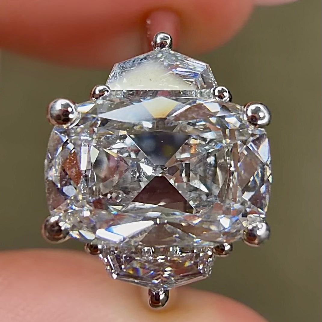 Close-up of a diamond earring held between fingers with a blurred background