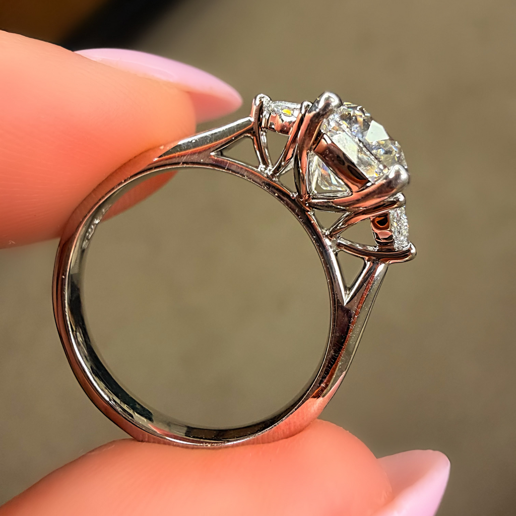 Silver ring with a diamond held between fingers against a neutral background
